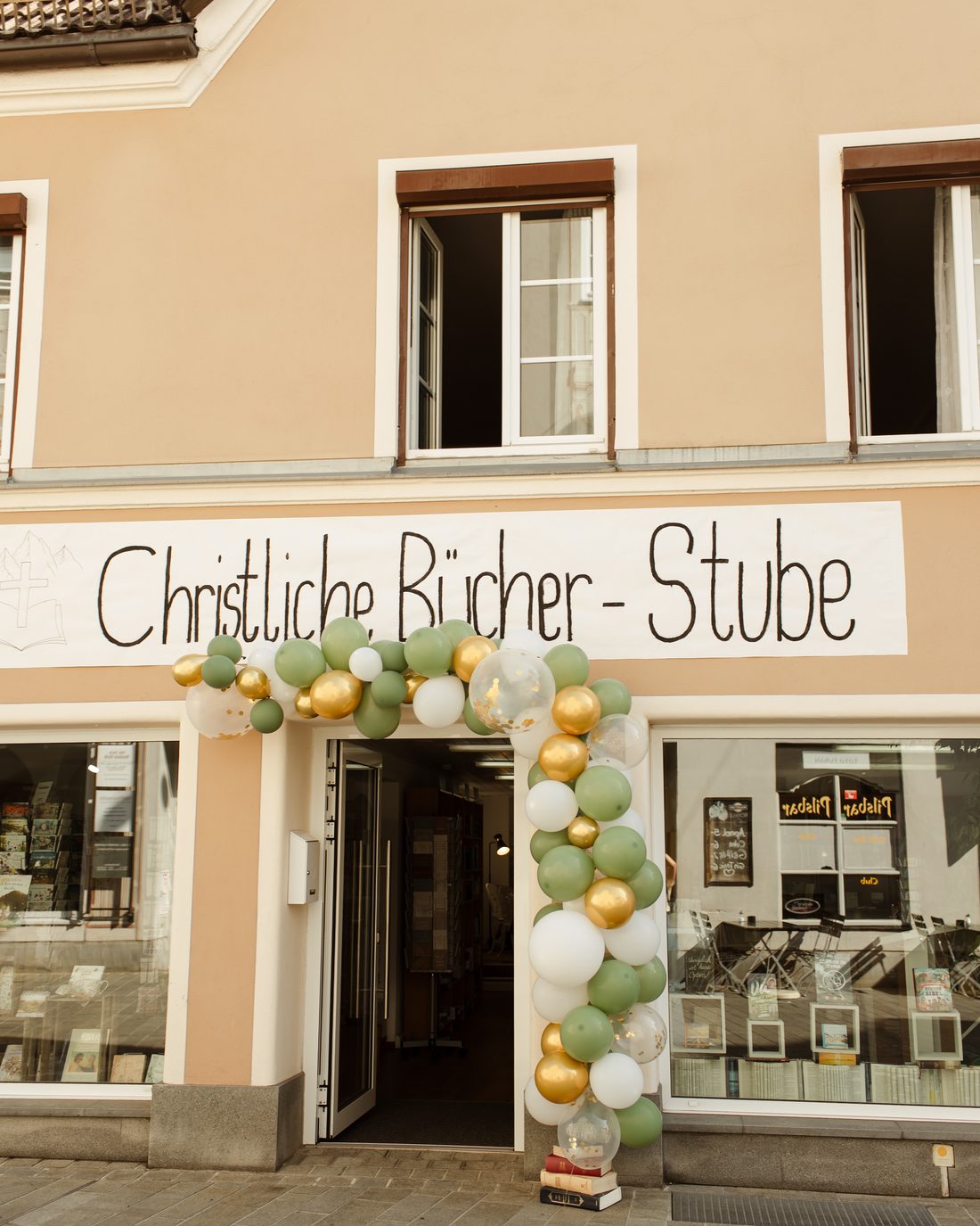 Ladenfront der Christlichen Bücher-Stube in der Gerberstraße 26 mit handgemaltem Schriftzug und Ballonbogen zur Eröffnung